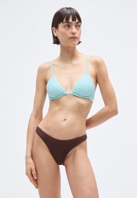 Top de bikini turcoaz cu dungi și bretele subțiri, cu slip de bikini maro cu dungi și talie joasă. Textură netedă și design minimalist.