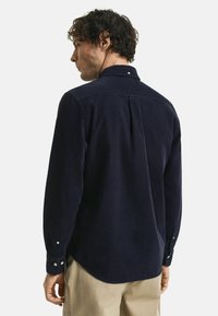Navy corduroy overhemd met een button-down kraag, lange mouwen met knoopmanchetten en een rugplooi voor vrij bewegingsgemak.