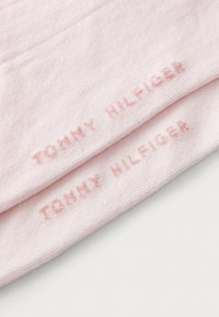 Šviesiai rožinės kojinės su minkšta tekstūra, kurių viršuje yra iškilūs „TOMMY HILFIGER“ logotipai, atitinkančios spalvos.