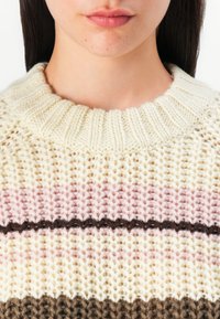 Maglione lavorato a maglia con collo a coste spesso. Presenta una base crema con strisce orizzontali pastello rosa e marroni. Design strutturato, caldo e voluminoso.
