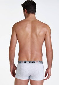 Szürke boxer alsónadrág, pamut keverékből készült, fekete és piros "GUESS" logós derékszíjjal, hátulról bemutatva, sima felülettel.