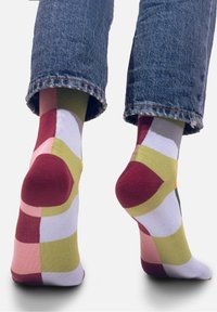 Kolorowe skarpetki crew z geometrycznym wzorem w odcieniach różu, maroon, zieleni i żółci, z kontrastującymi palcami i piętami.