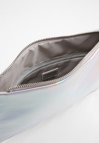 Irydescencyjna kosmetyczka z zamkiem błyskawicznym, srebrnym wykończeniem i wewnętrzną kieszonką. Gładka tekstura i elegancki design.
