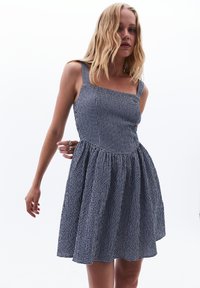 Neliökauluksellinen mekko, jossa on tummansininen ja valkoinen ruudullinen kuvio, varustettuna istuvalla yläosalla ja levenevällä hameella, valmistettu kevyestä kankaasta.