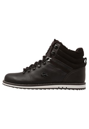 Bottine noire en cuir mi-haute avec doublure en fourrure, laçage à l’avant avec œillets métalliques, col de cheville rembourré et semelle blanche rainurée.
