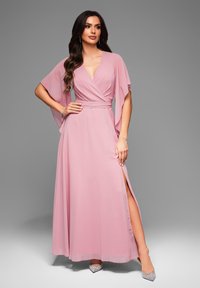 Rosa chiffongklänning med djup V-ringning och breda kimonoärmar. Har ett midjeband och slits på sidan, kompletterad med smyckade klackar.