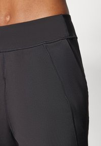 Zwarte sportleggings met een gladde textuur, hoge tailleband en platte stikseldetails. Ontworpen voor comfort en flexibiliteit.