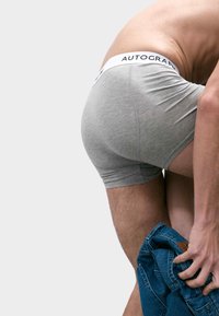 Boxer in cotone grigio con vita bianca su cui è impresso il logo "AUTOGRAPH". Il modello sta indossando dei jeans in denim blu.