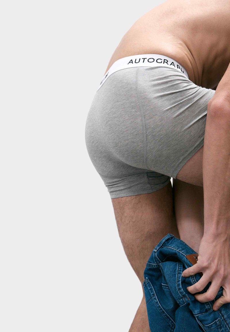 Boxer in cotone grigio con vita bianca su cui è impresso il logo "AUTOGRAPH". Il modello sta indossando dei jeans in denim blu.