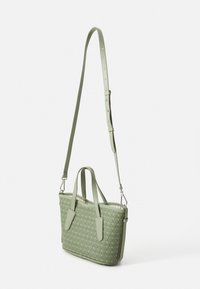 Green leather handbag with adjustable strap and twin handles. Features embossed pattern and zip closure. Textured finish.