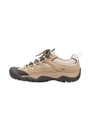 Chaussure de randonnée beige et marron clair avec semelle extérieure noire, œillets métalliques, panneaux en mesh et lacets épais et ronds sur fond blanc.