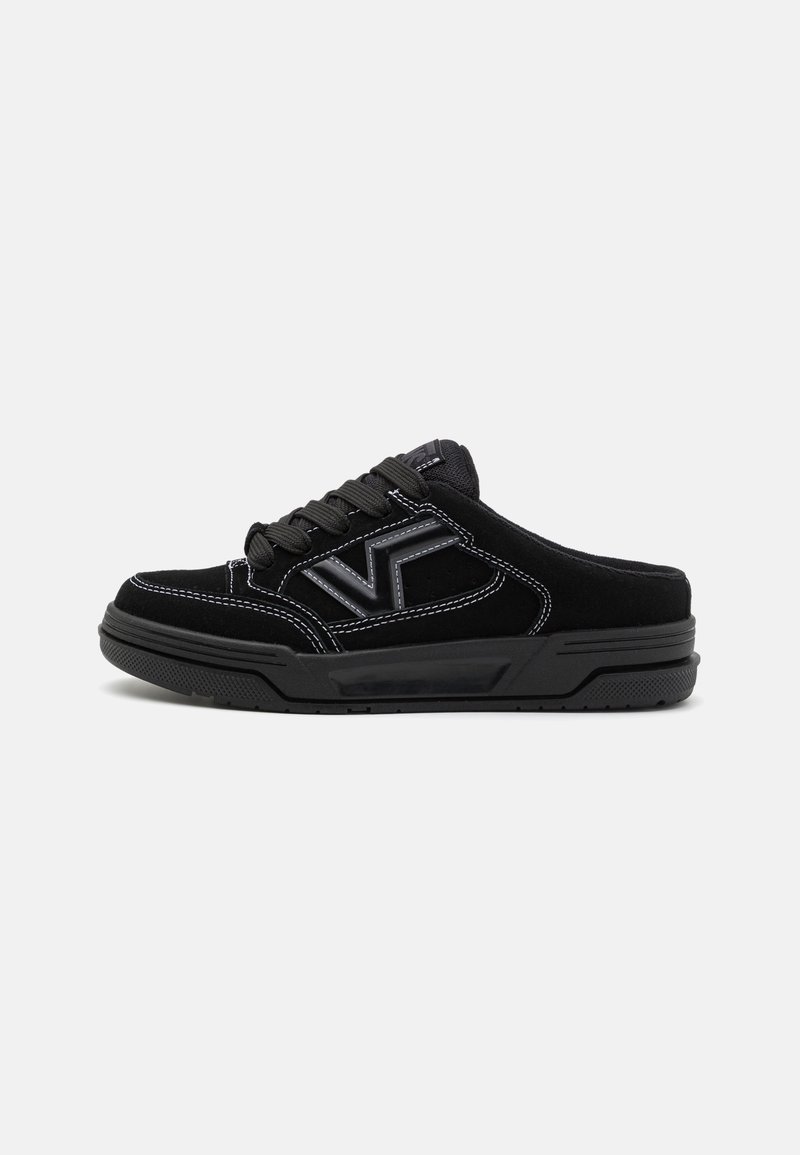 Baskets slip-on noires avec lacets, coutures blanches visibles, semelle épaisse et logo "VF" sur le côté, montrées de profil sur un fonds clair.