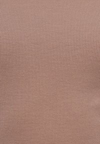 Ριμπ πλεκτό τοπ σε απαλό ροζ χρώμα. Διαθέτει υφή με κάθετες γραμμές. Το ύφασμα φαίνεται ελαστικό και ελαφρύ. Χωρίς επιπλέον λεπτομέρειες.