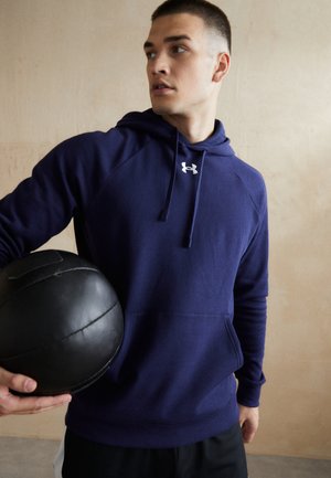Navy blue hooded sweatshirt made of soft fabric, featuring a front pocket, ribbed cuffs, and a small white logo on the chest.