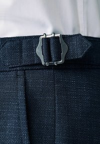 Cinturón de tela de color navy con un acabado texturizado, que presenta una hebilla metálica de color plata con un diseño angular, aplicado a pantalones de sastre.