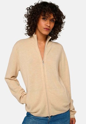 Pull homme beige zippé en tissu doux, doté d'un col montant et de manches longues, avec une coupe décontractée et une texture lisse.