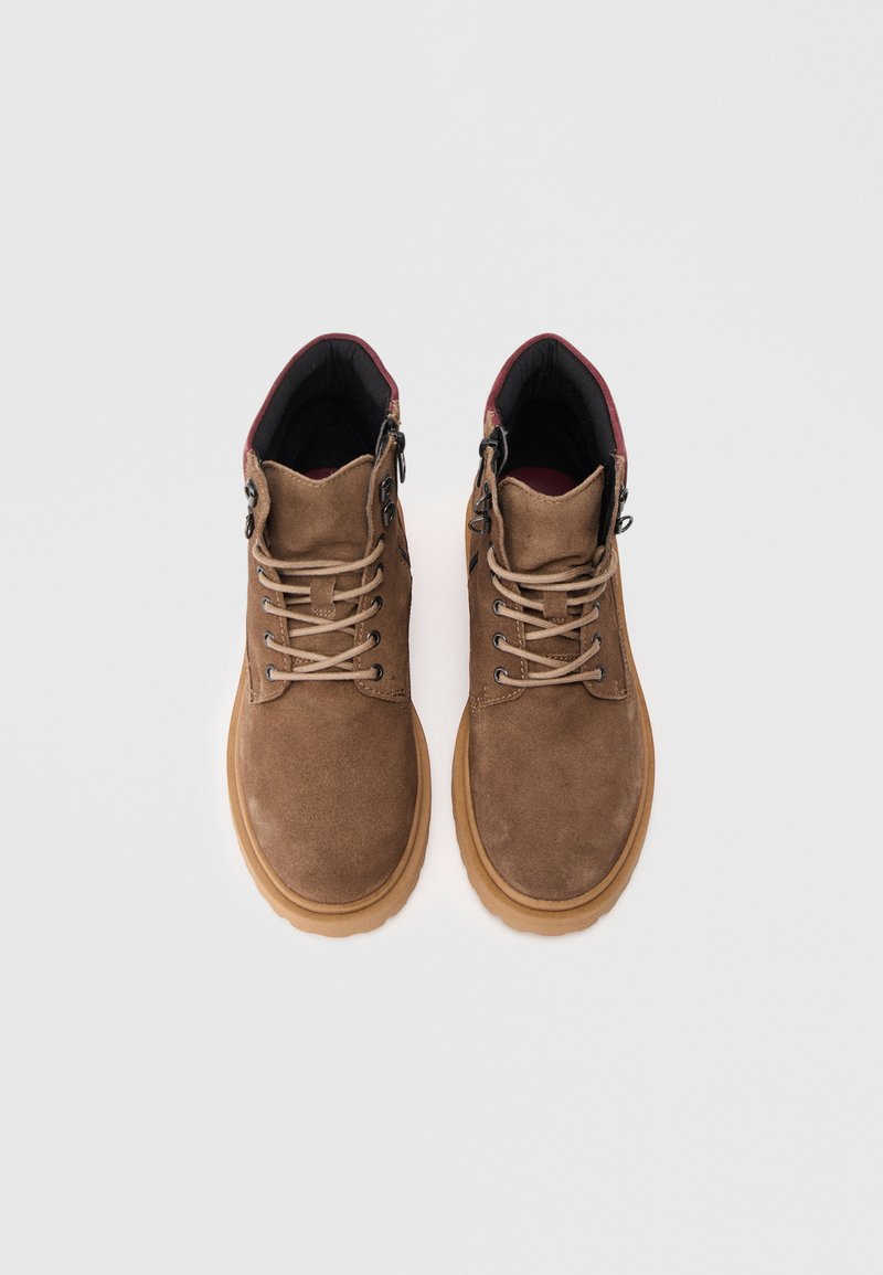 Brown suede ankle boots with a textured surface, beige laces, black and burgundy lining, and a tan rubber sole. Features metal eyelets.