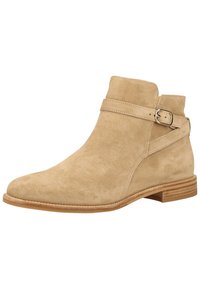 Beige Wildleder-Ankle Boot mit seitlichem Schnallenriemen, runder Zehenpartie und niedrigem, gestapeltem Absatz. Glatte Textur mit Nähakzenten entlang der Kanten.