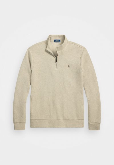 Šviesiai beige spalvos megztinis su ketvirčio užtrauktuku, ilgomis rankovėmis ir mažą išsiuvinėtų logotipo detalę krūtinėje. Minkšta, tekstūrinė medžiaga.