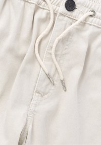 Light beige shorts with a textured fabric, featuring a drawstring closure, a black button, and subtle stitching details.