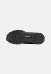 Schwarze Schuhsohle mit tiefen, kantigen Profilmustern für gute Bodenhaftung. Mit gelber Continental-Branding auf einer strukturierten Oberfläche.