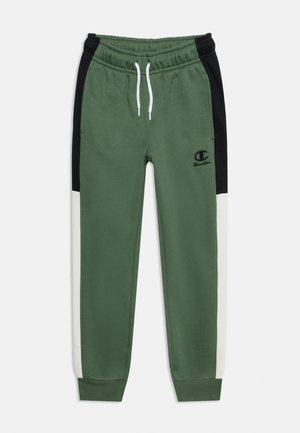 Grønne joggingbukser med sorte og hvide sidelister, hvid snor i linningen og sort Champion-logo på venstre lår.