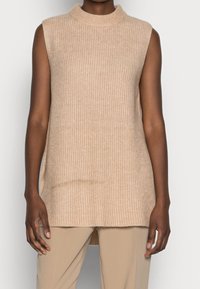 Débardeur en maille sans manches de couleur beige clair avec un col haut, doté d'une texture côtelée et de fentes latérales pour faciliter les mouvements.