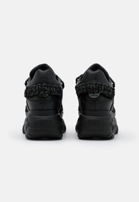 Svarta sneakers med övre delar i texturerat läder, flätat hälldetalj och en kraftig gummisula med mönstrad slitbana.