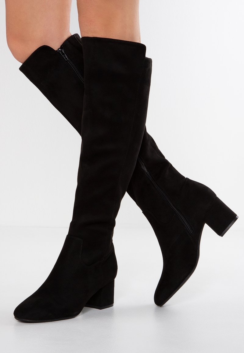 Bottes noires hautes jusqu'au-dessus du genou en daim. Bout carré et talon bloc, avec une fermeture éclair extérieure pour un enfilage facile. Texture lisse.