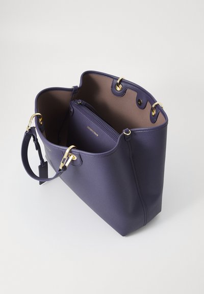 Purple tote bag with gold hardware, open to reveal a smooth, beige lining and an inner zippered compartment for organization.