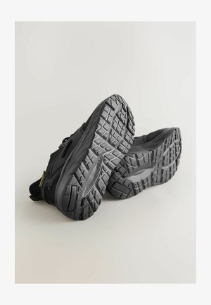 Scarpe sportive nere con suole in gomma texturizzata, caratterizzate da un design elegante e suola a motivo per una migliore aderenza e trazione.