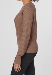 Teksturowany brązowy sweter z okrągłym dekoltem, prążkowanymi mankietami i dołem. Ma dzianinowy wzór w zygzak oraz dopasowany krój.