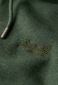 Felpa con cappuccio in tessuto verde scuro dalla consistenza morbida. Presenta un logo "SuperDry" ricamato in evidenza tono su tono.