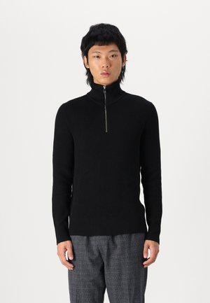 Črn rebrast zip-up pulover z visokim ovratnikom in dolgimi rokavi, ki ima tanek srebrn zadrgo in prilegajoč silhueto. Teksturirana tkanina.