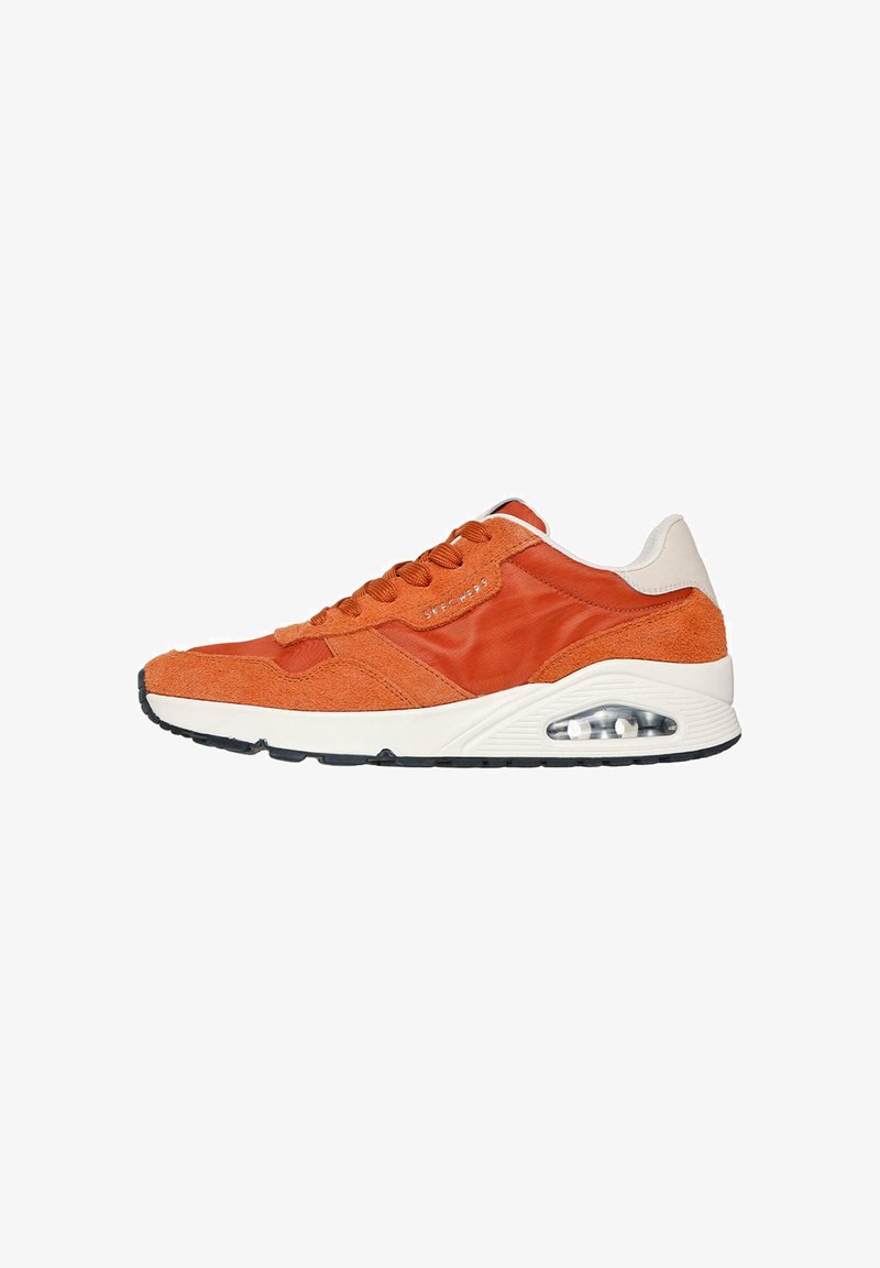 Baskets de sport orange et beige avec un devant à lacets, coussin d'air visible dans la semelle et semelle noire en bas.