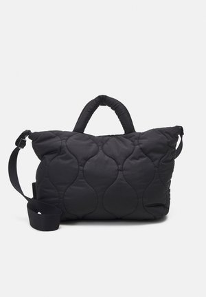 Sac fourre-tout en tissu matelassé noir avec anses courtes rembourrées et une bandoulière réglable sur fond blanc.