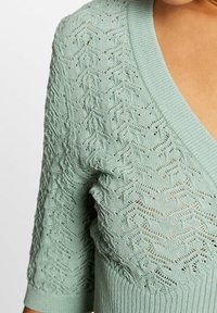 Licht mintgroene gebreide cardigan met een textuur, opengewerkte patroon, v-hals en ribgebreide manchetten. Zacht, lichtgewicht materiaal.