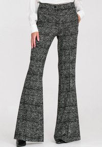 Czarno-białe spodnie z rozszerzanymi nogawkami, ozdobione teksturowanym wzorem. Mają wysoki stan i boczne kieszenie, noszone z białym topem i szpilkami.