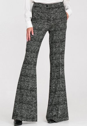 Czarno-białe spodnie z rozszerzanymi nogawkami, ozdobione teksturowanym wzorem. Mają wysoki stan i boczne kieszenie, noszone z białym topem i szpilkami.