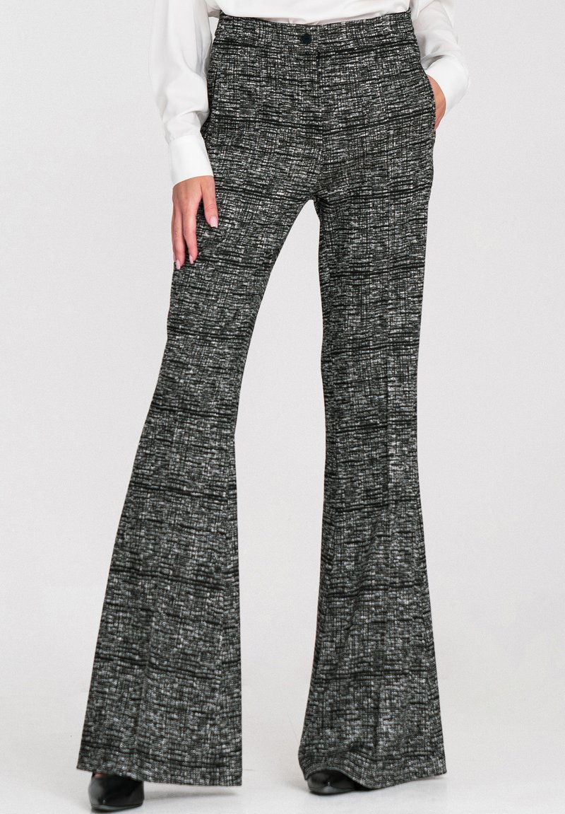 Czarno-białe spodnie z rozszerzanymi nogawkami, ozdobione teksturowanym wzorem. Mają wysoki stan i boczne kieszenie, noszone z białym topem i szpilkami.