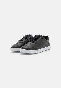 Black leather sneakers with a rounded toe, white rubber outsole, and black laces. Smooth texture with minimal design details.