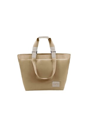 Beige tote bag med slitesterkt stoff, doble korte håndtak og kontrastfarget metall. Har en liten logo på den ene siden. Rektangulær form.