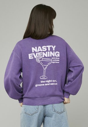 Sweatshirt violet à coupe oversize, avec un graphique blanc d'un verre à cocktail et le texte "NASTY EVENING" imprimé au dos.