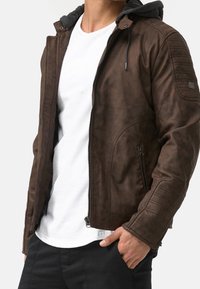 Brown leather jacket with a gray hood. Features a smooth texture, zipper closure, side pockets, and quilted detailing on shoulders.