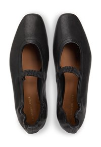 Μαύρα δερμάτινα φλατ παπούτσια με τετράγωνη μύτη, ελαστικό λουράκι και στρογγυλεμένες άκρες. Το εσωτερικό παρουσιάζει μια λεία καφέ επιφάνεια με ανάγλυφη επωνυμία.