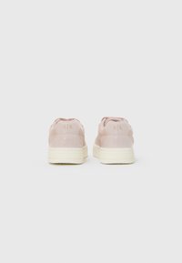 Sneaker in pelle lucida rosa con suola in gomma crema, caratterizzati da un retro texturizzato e accenti dorati del logo sul tallone.