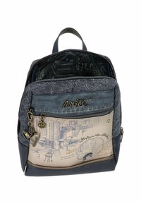 Mochila con una parte superior texturizada en azul marino, una sección inferior en crema con bocetos artísticos, acentos metálicos y un compartimento con cremallera.