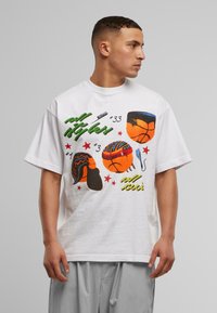 Hvit bomulls T-skjorte med fargerike grafiske design av basketballer og frisyrer, med grønne og røde detaljer, oversized passform.