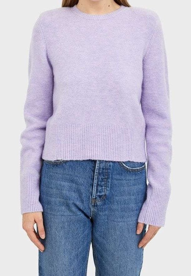Femme portant un pull duveteux lavande à col rond avec poignets et ourlet côtelés, associé à un jean bleu taille haute.