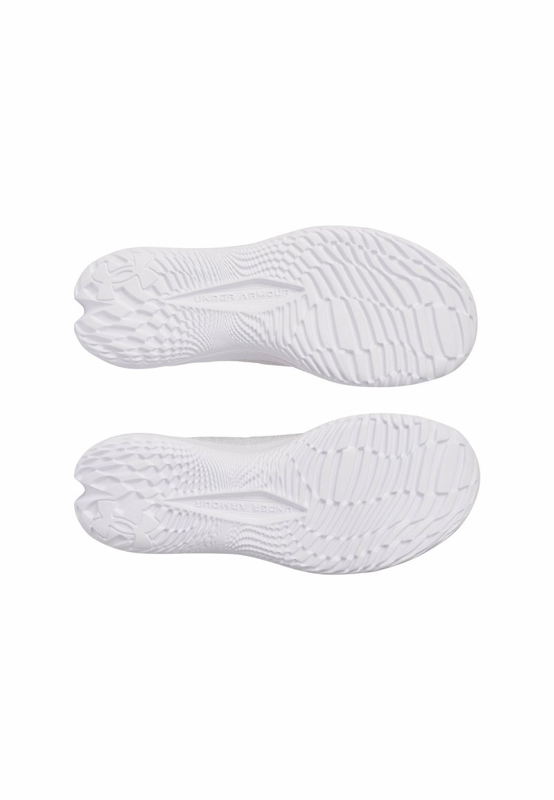 Semelles de chaussures de sport blanches présentant un motif de grip texturé et un design de semelle prononcé, avec un marquage sur la semelle intermédiaire.